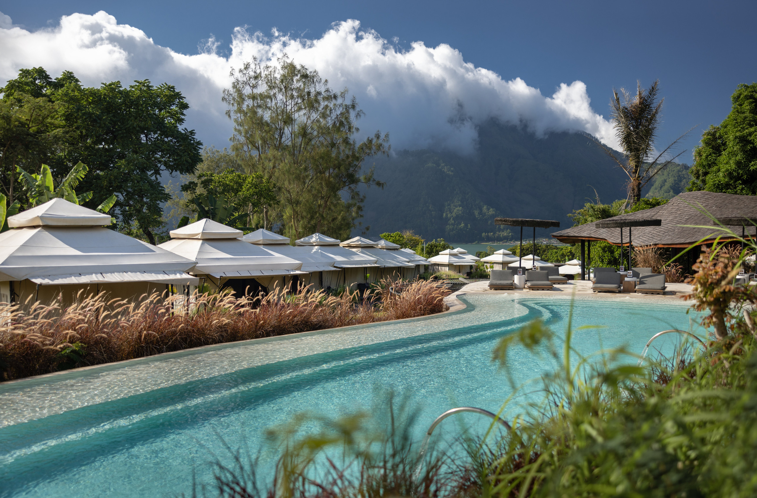 Tents beside the natural hot spring pool at Toteme Glamping with a Kintamani mountain backdrop
